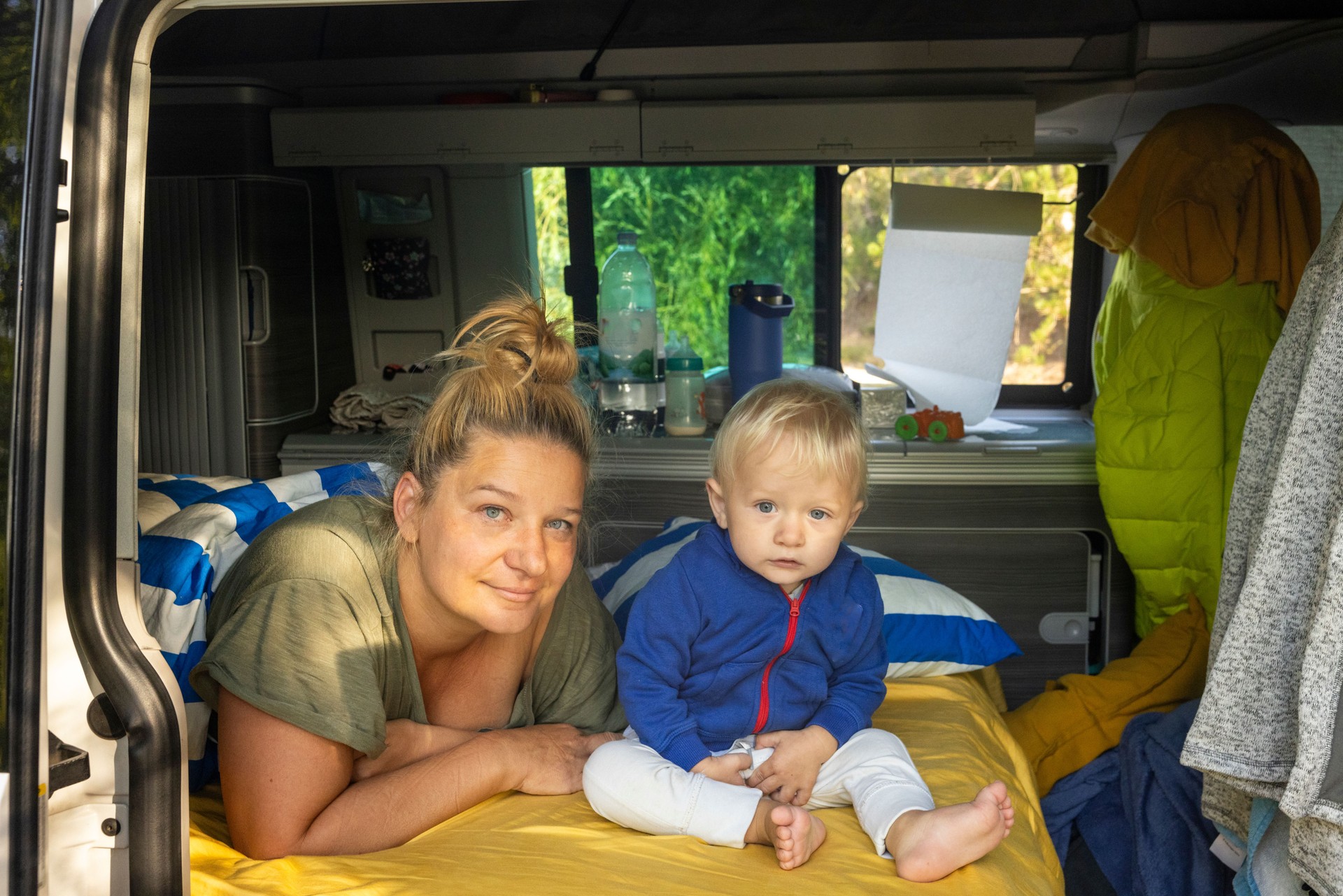 Mother and Son Relaxing on Bed in Open Camper Van,Enjoying Cozy Moments