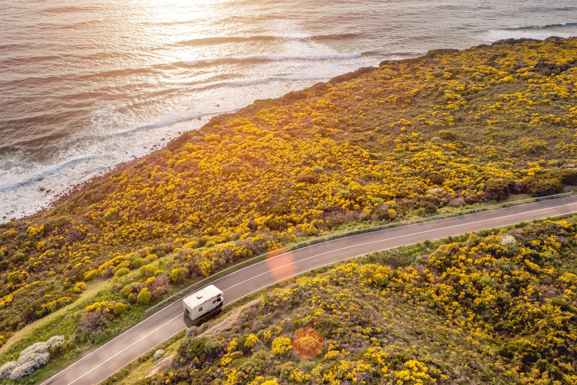 Motorhome on a road by the sea at sunset, aerial view