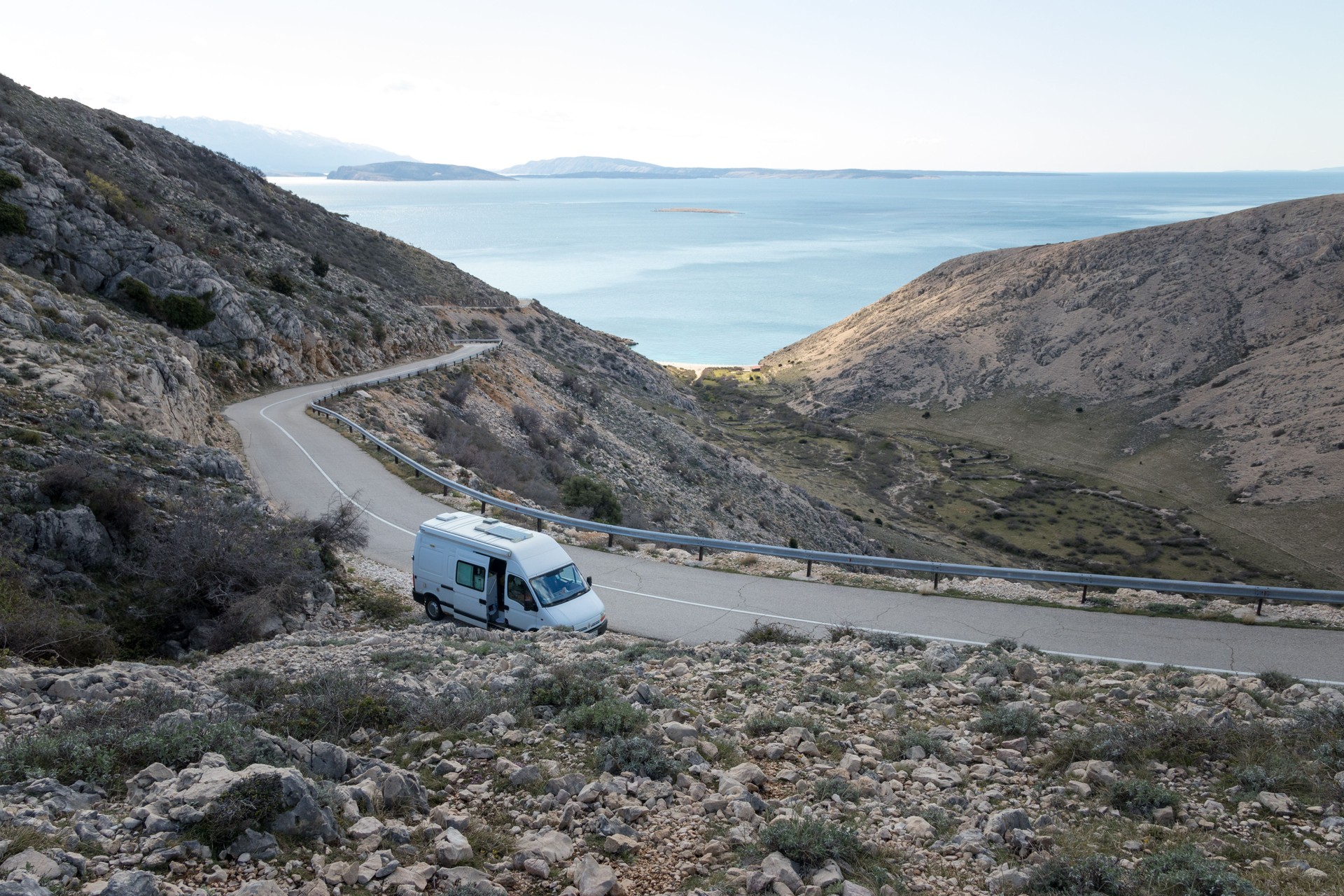 Camper van parked by the road above the sea